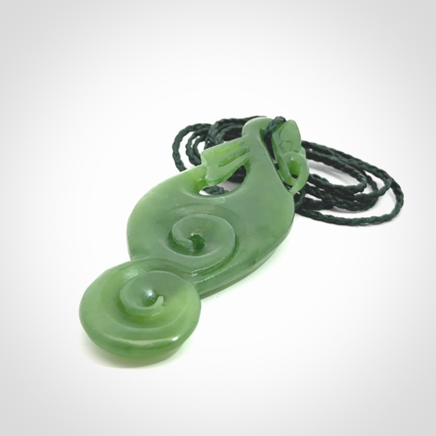 This pendant is a beautiful large New Zealand Auhunga green jade manaia pendant with koru. It has the head of a bird and the tail of a fish and also two koru carved into the body. It is carved by Ross Crump here in New Zealand. Provided with an adjustable manuka green cord.