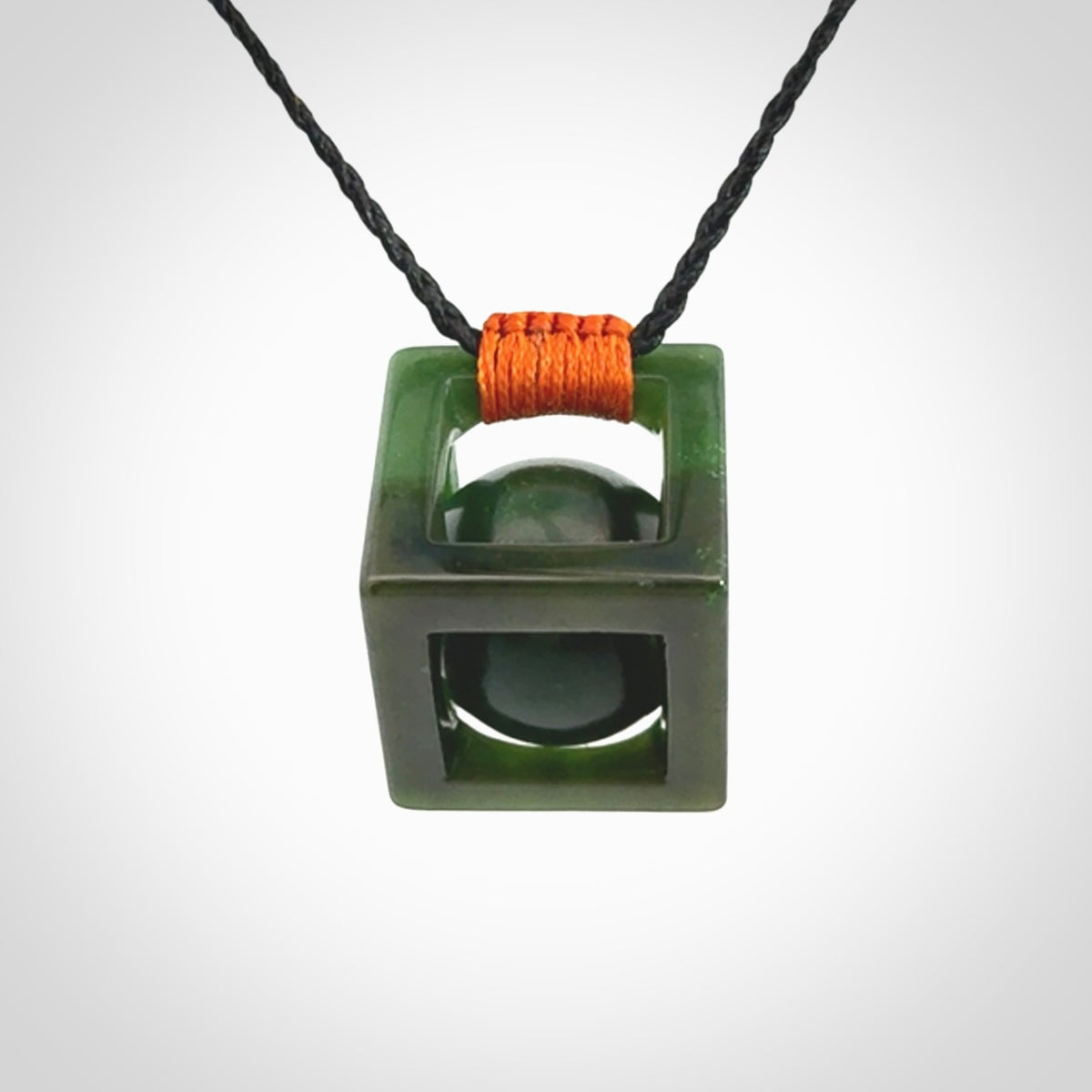A hand carved medium sized green Jade square box with ball inside necklace. The cord is adjustable in length. A medium sized hand made cube/box with ball necklace in green Jade.