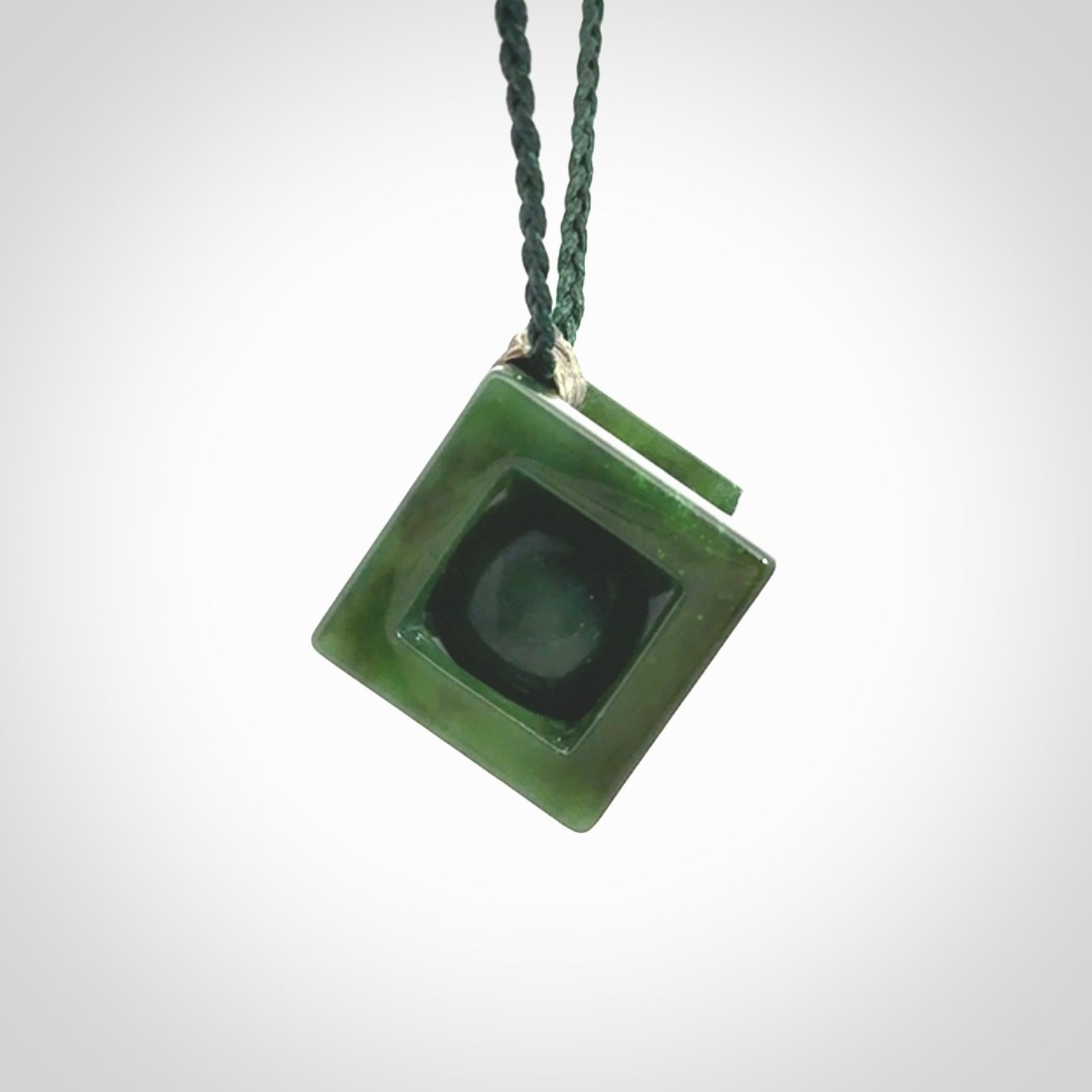 A hand carved medium sized green Jade square box with ball inside necklace. The cord is adjustable in length. A medium sized hand made cube/box with ball necklace in green Jade.