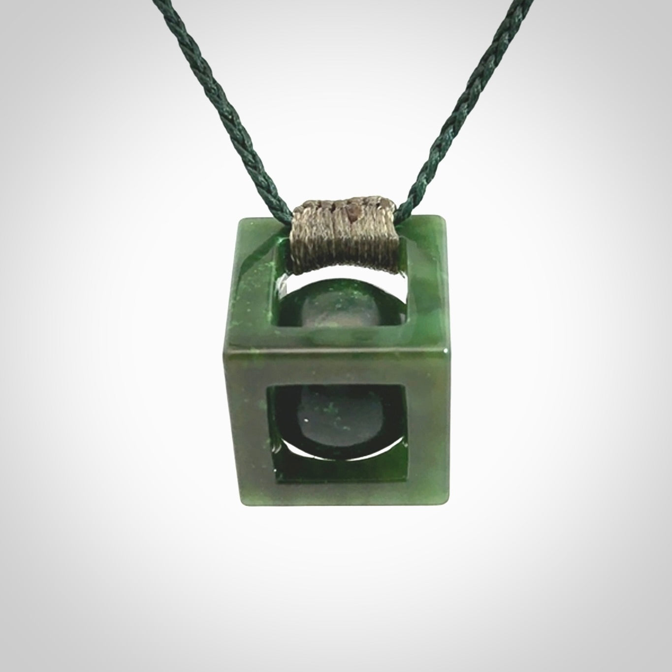 A hand carved medium sized green Jade square box with ball inside necklace. The cord is adjustable in length. A medium sized hand made cube/box with ball necklace in green Jade.
