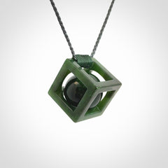 A hand carved medium sized green Jade square box with ball inside necklace. The cord is adjustable in length. A medium sized hand made cube/box with ball necklace in green Jade.