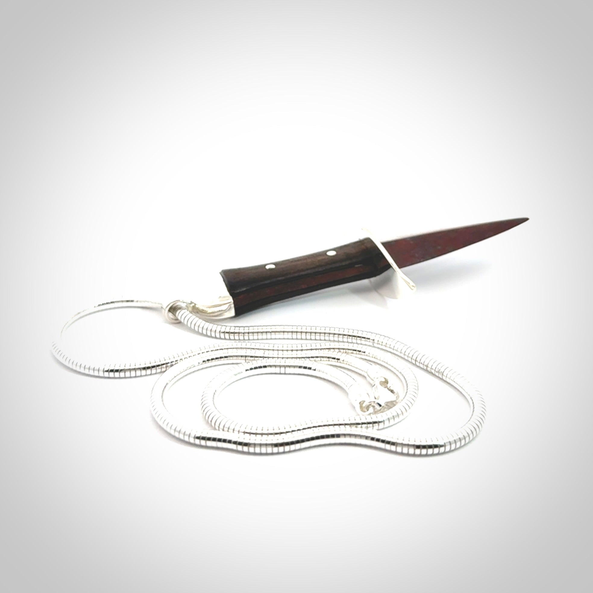 A striking hand carved dagger pendant. These are carved with a Red Jasper Stone head and a hardwood handle. It is provided with a Sterling Silver chain. We ship these worldwide with express courier.