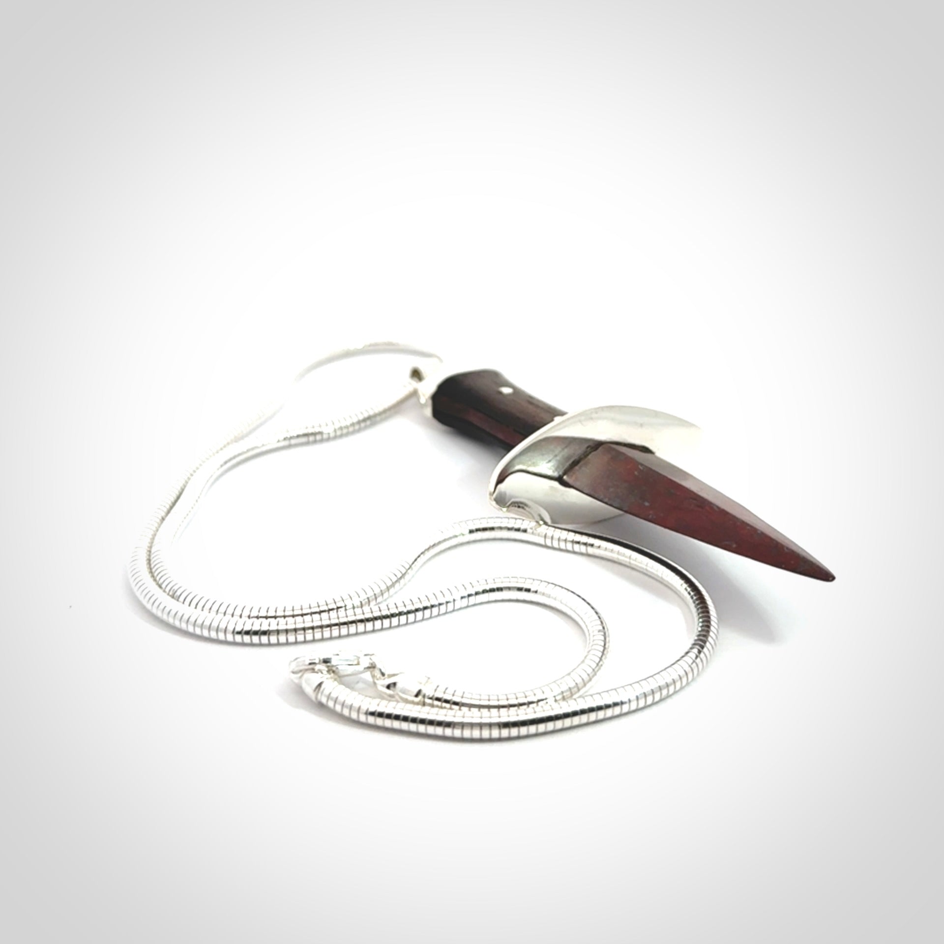 A striking hand carved dagger pendant. These are carved with a Red Jasper Stone head and a hardwood handle. It is provided with a Sterling Silver chain. We ship these worldwide with express courier.
