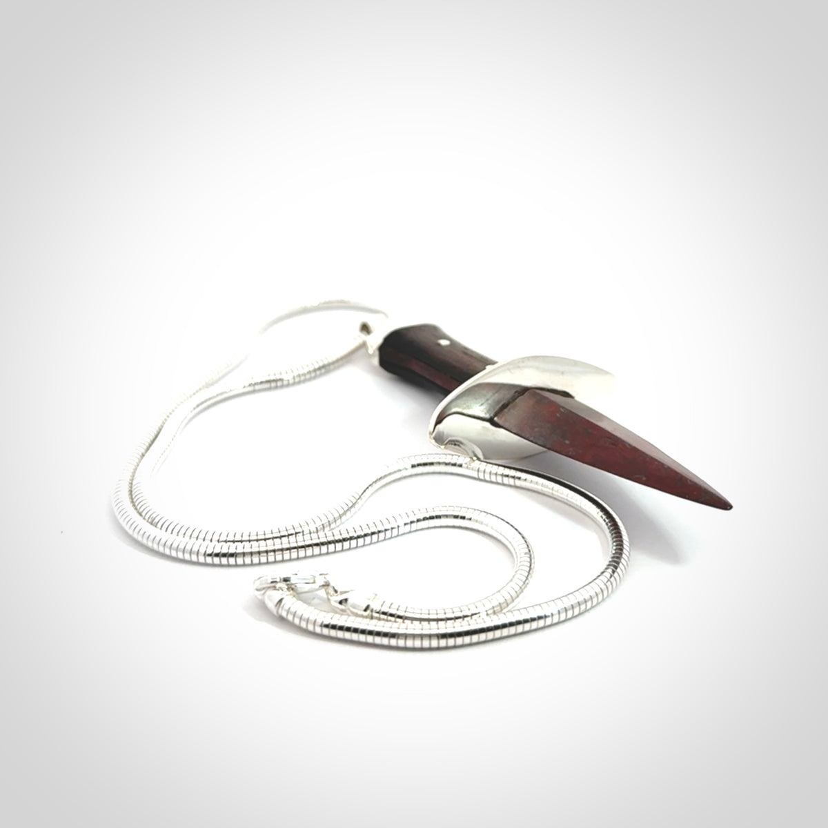 A striking hand carved dagger pendant. These are carved with a Red Jasper Stone head and a hardwood handle. It is provided with a Sterling Silver chain. We ship these worldwide with express courier.