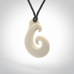 Hand carved bone koru pendant hand made by Peter Mitchell in New Zealand. This bone koru is provided with an adjustable black cord and packaged in a woven kete pouch.