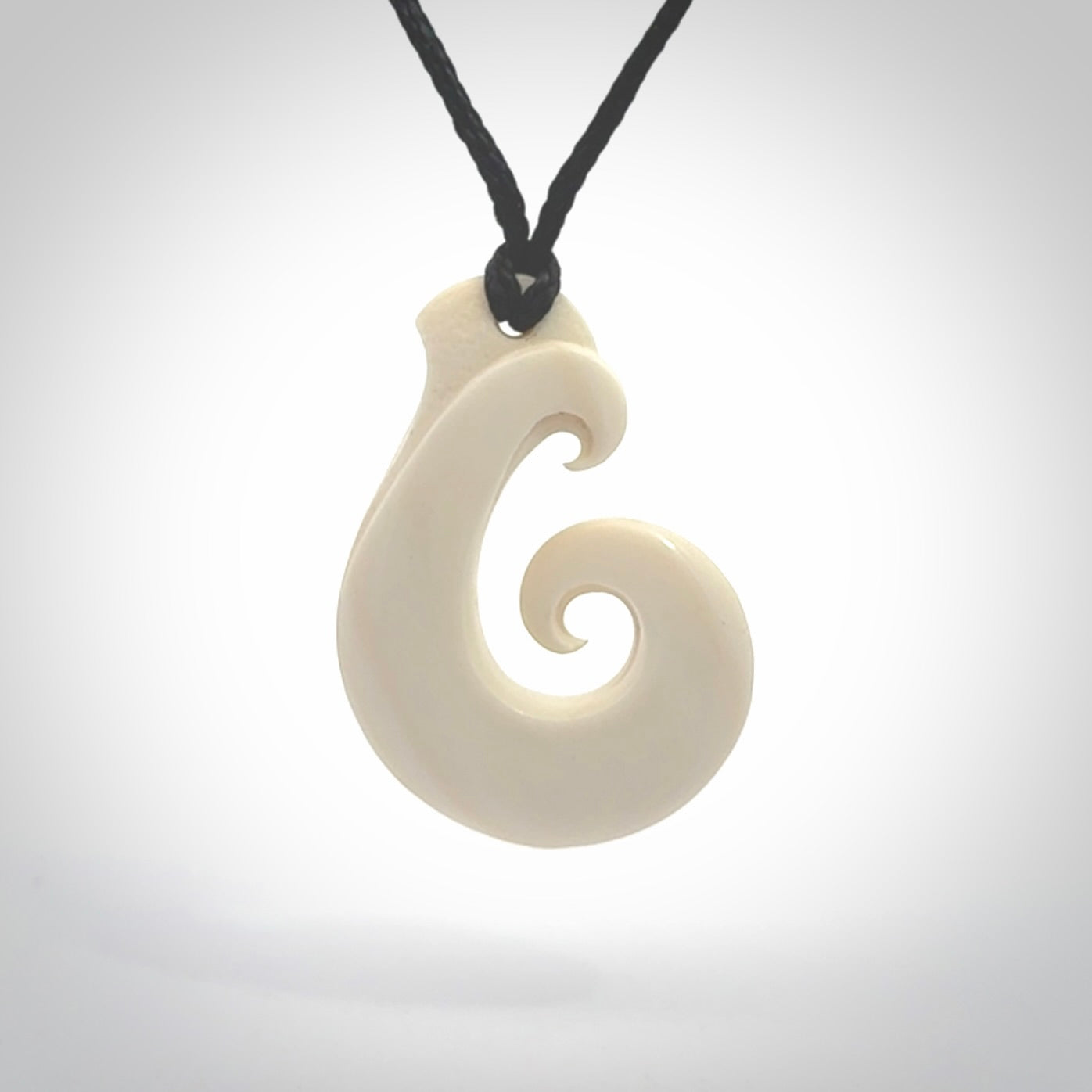 Hand carved bone koru pendant hand made by Peter Mitchell in New Zealand. This bone koru is provided with an adjustable black cord and packaged in a woven kete pouch.
