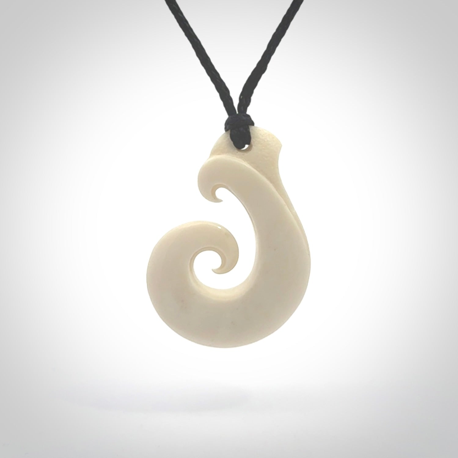 Hand carved bone koru pendant hand made by Peter Mitchell in New Zealand. This bone koru is provided with an adjustable black cord and packaged in a woven kete pouch.