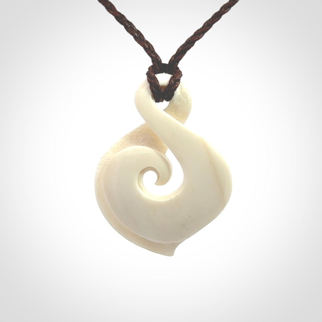 Hand carved bone twist pendant hand made by Peter Mitchell in New Zealand. This bone twist is provided with an adjustable brown cord and packaged in a woven kete pouch.