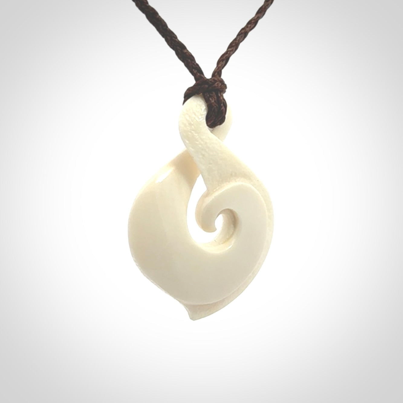 Hand carved bone twist pendant hand made by Peter Mitchell in New Zealand. This bone twist is provided with an adjustable brown cord and packaged in a woven kete pouch.