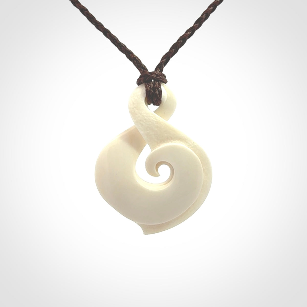 Hand carved bone twist pendant hand made by Peter Mitchell in New Zealand. This bone twist is provided with an adjustable brown cord and packaged in a woven kete pouch.