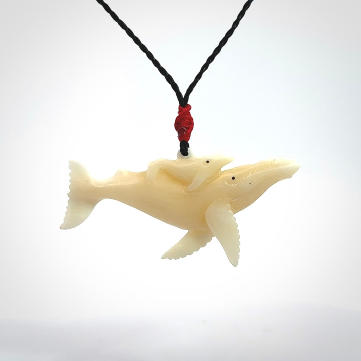 Hand carved bone whale and whale calf pendant