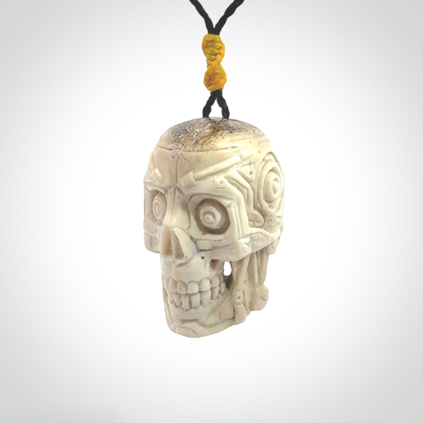 This picture shows a medium sized Deer Antler Bone robot skull pendant that we have hand carved. The cord is a black colour and has a small yellow binding just above the pendant.
