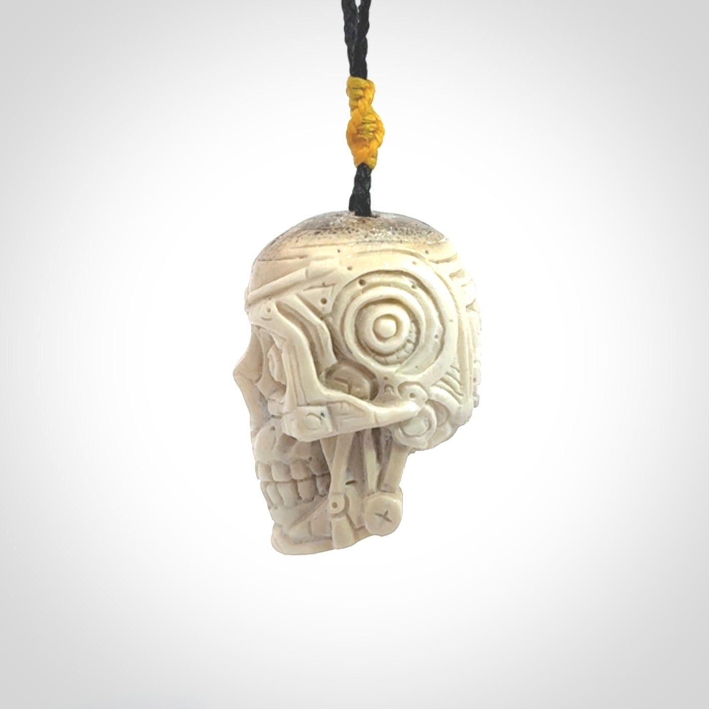 This picture shows a medium sized Deer Antler Bone robot skull pendant that we have hand carved. The cord is a black colour and has a small yellow binding just above the pendant.
