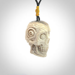 This picture shows a medium sized Deer Antler Bone robot skull pendant that we have hand carved. The cord is a black colour and has a small yellow binding just above the pendant.