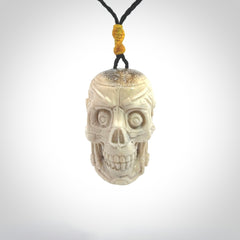 This picture shows a medium sized Deer Antler Bone robot skull pendant that we have hand carved. The cord is a black colour and has a small yellow binding just above the pendant.