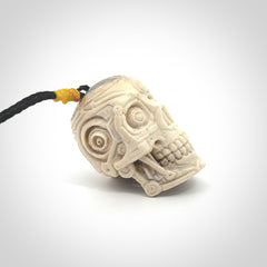 This picture shows a medium sized Deer Antler Bone robot skull pendant that we have hand carved. The cord is a black colour and has a small yellow binding just above the pendant.