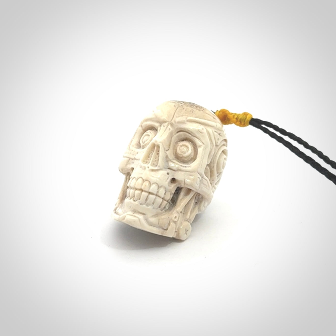 This picture shows a medium sized Deer Antler Bone robot skull pendant that we have hand carved. The cord is a black colour and has a small yellow binding just above the pendant.