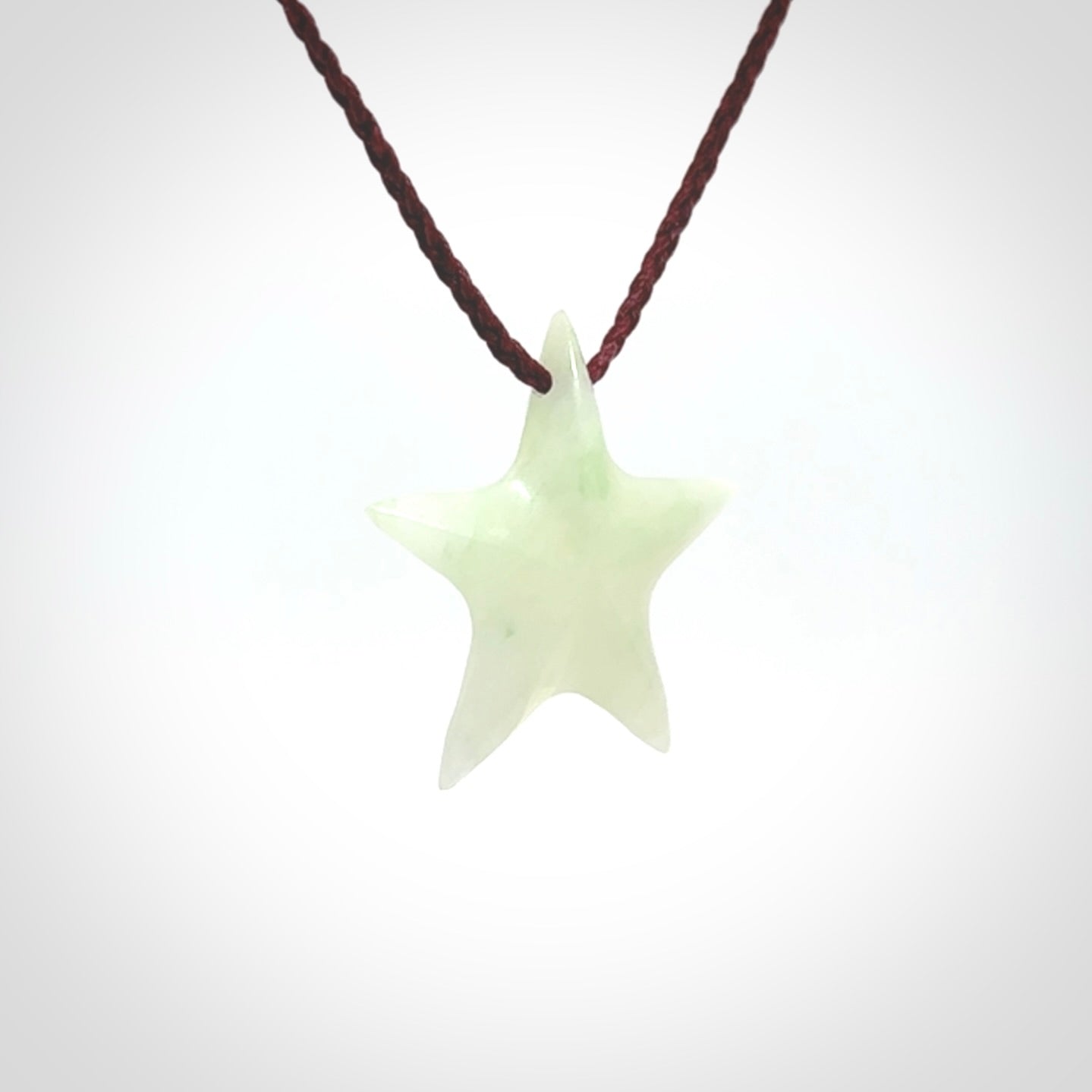 Small Jadeite star pendant. Star shaped necklace hand made from white Jadeite stone. Delivered on an adjustable plum coloured cord and packaged in a woven kete pouch.