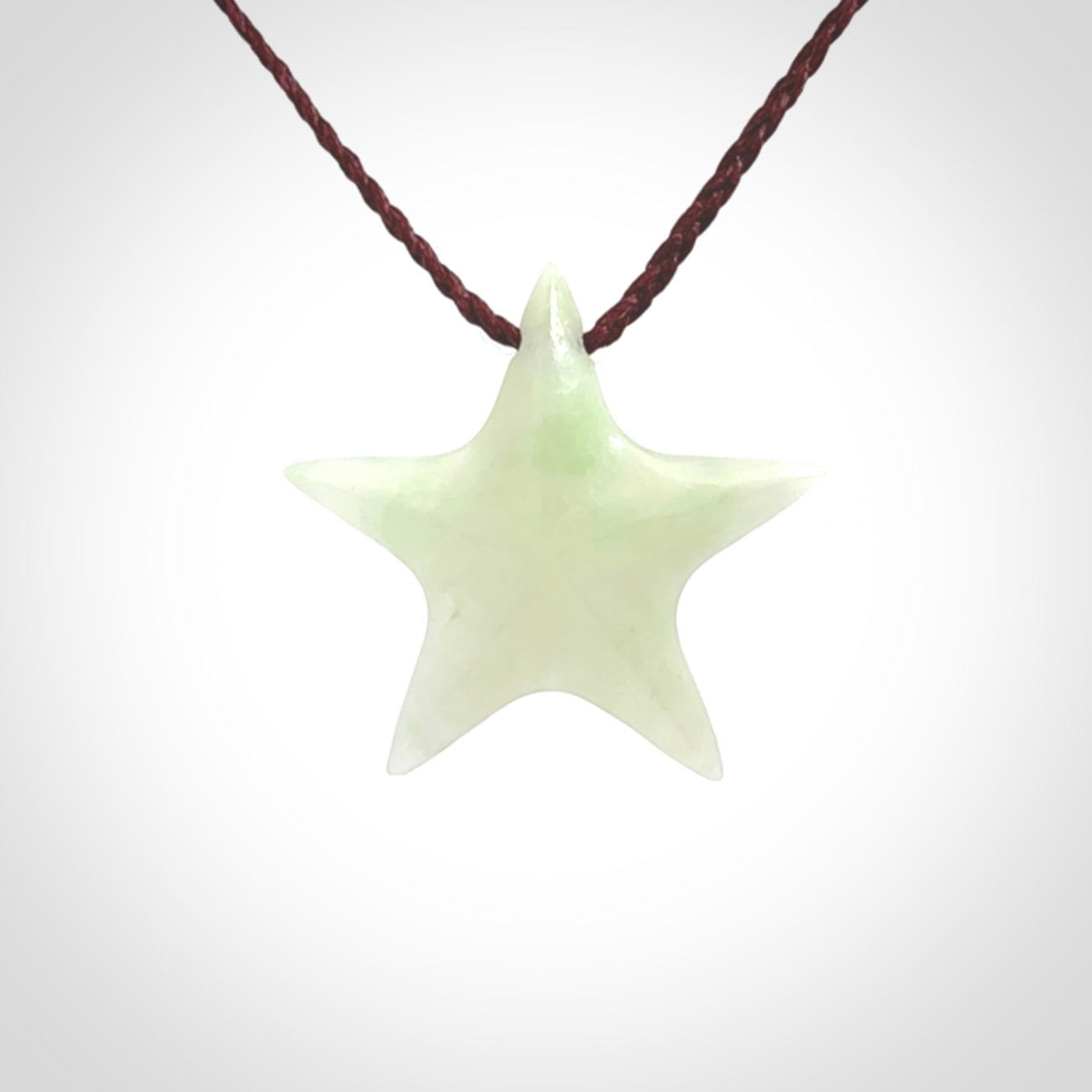 Small Jadeite star pendant. Star shaped necklace hand made from white Jadeite stone. Delivered on an adjustable plum coloured cord and packaged in a woven kete pouch.