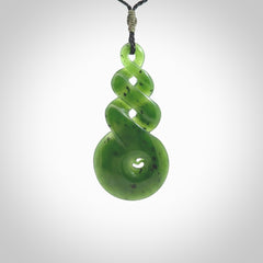 Ross Crump triple twist with koru pendant. Hand carved from rare New Zealand jade this is a beautiful pounamu pendant. The cord is length adjustable. It is a delicate and very beautiful greenstone pendant. For sale online by NZ Pacific.