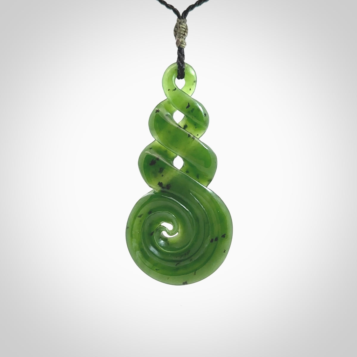 Ross Crump triple twist with koru pendant. Hand carved from rare New Zealand jade this is a beautiful pounamu pendant. The cord is length adjustable. It is a delicate and very beautiful greenstone pendant. For sale online by NZ Pacific.