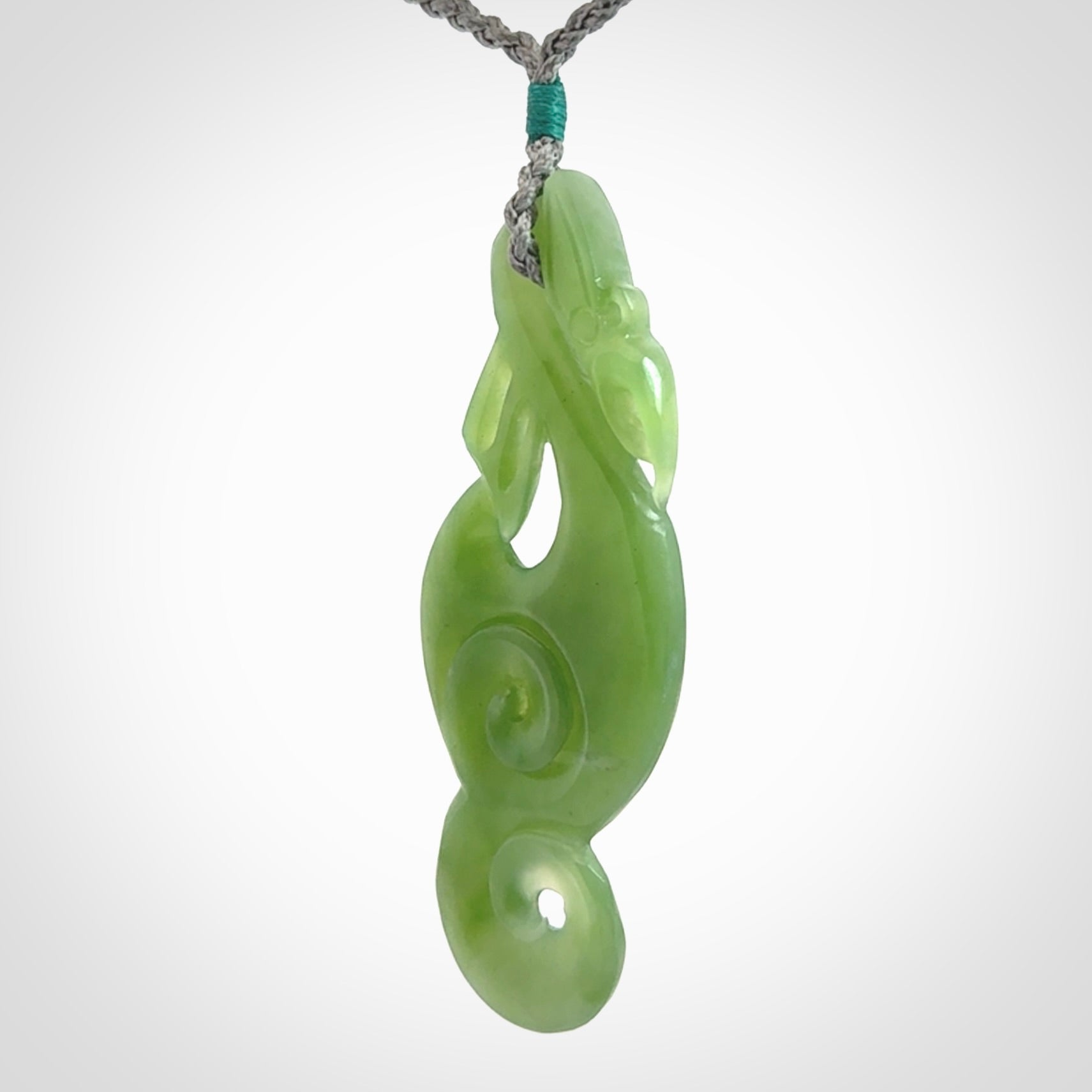 This pendant is a beautiful large New Zealand Inanga jade manaia pendant with koru. It has the head of a bird and the tail of a fish and also two koru carved into the body. It is carved by Ross Crump here in New Zealand. Provided with an adjustable Grey cord.