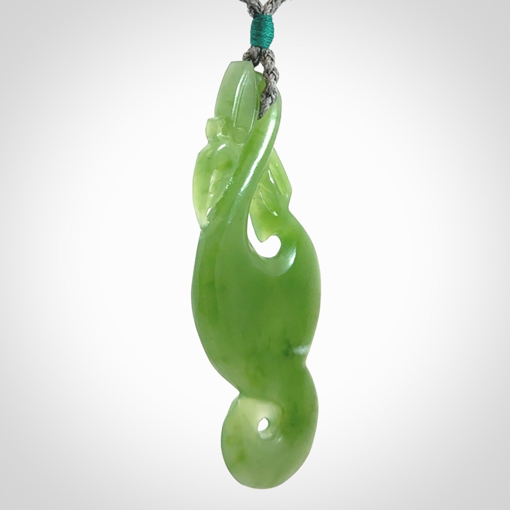 This pendant is a beautiful large New Zealand Inanga jade manaia pendant with koru. It has the head of a bird and the tail of a fish and also two koru carved into the body. It is carved by Ross Crump here in New Zealand. Provided with an adjustable Grey cord.