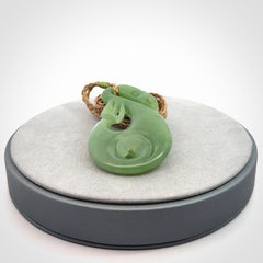 Hand carved New Zealand Inanga jade manaia with koru pendant. Carved from beautiful New Zealand Jade for NZ Pacific by Ross Crump. Unique jade jewellery for sale online. Provided with an adjustable tan cord.
