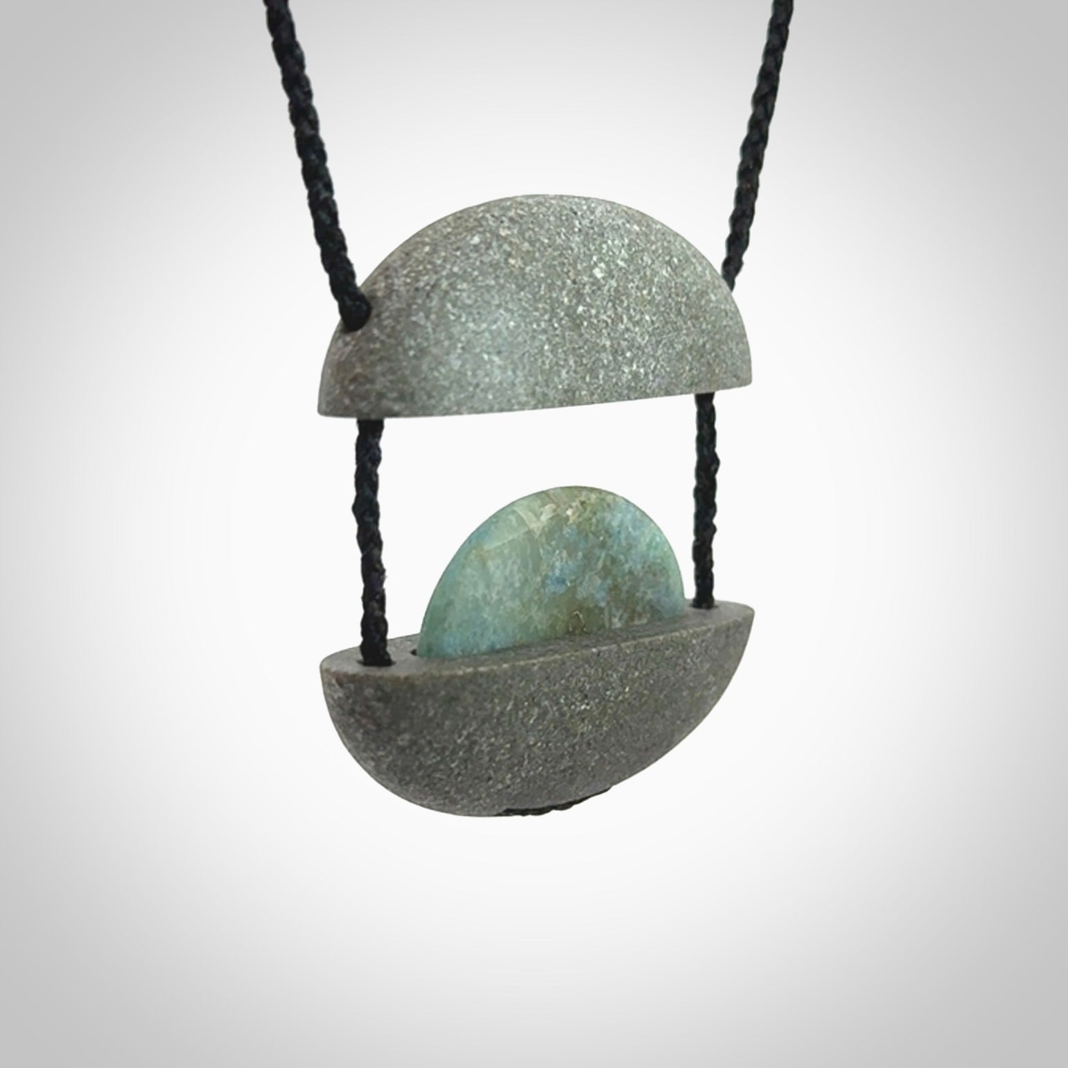 Greywacke stone pendant with Aotea Stone insert. Hand carved by Rhys Hall for NZ Pacific. Handmade contemporary jewellery for sale online.