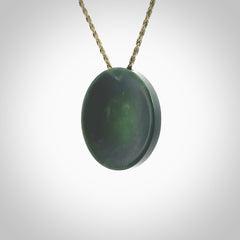 This piece is a oval round, cupped disc pendant. It was carved for us by Ric Moor from a lovely dark green piece of New Zealand jade. It is suspended on a khaki coloured braided cord that is length adjustable.