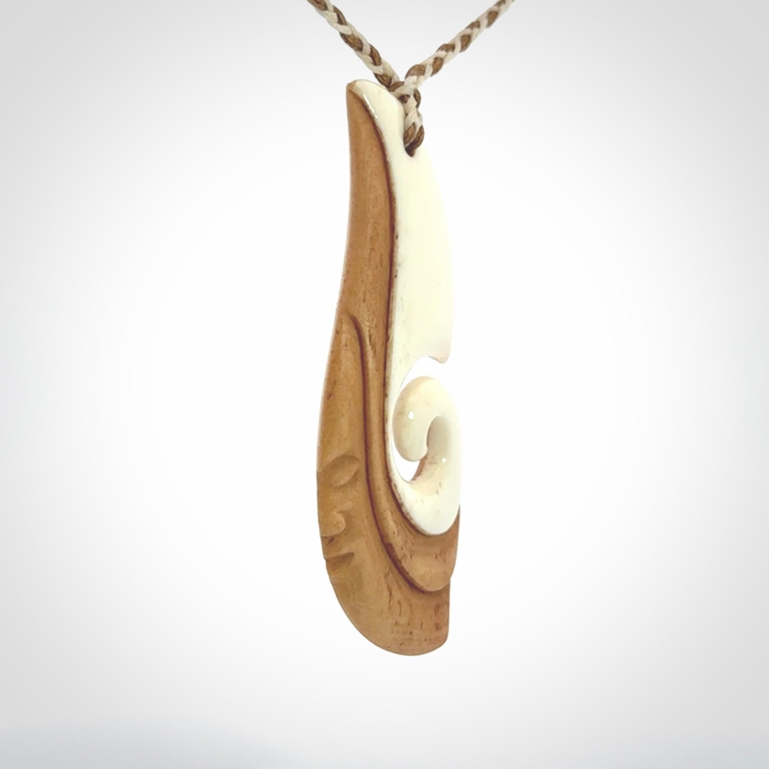 A hand carved bone contemporary, intricate pendant. The cord is a 4 strand, 3 plait in Ice White and Tan and is an adjustable length. A large sized hand made contemporary necklace by New Zealand artist Kerry Thompson. Kerry has stained parts of the bone which really add to the dimension of this pendant. One of work of art to wear.