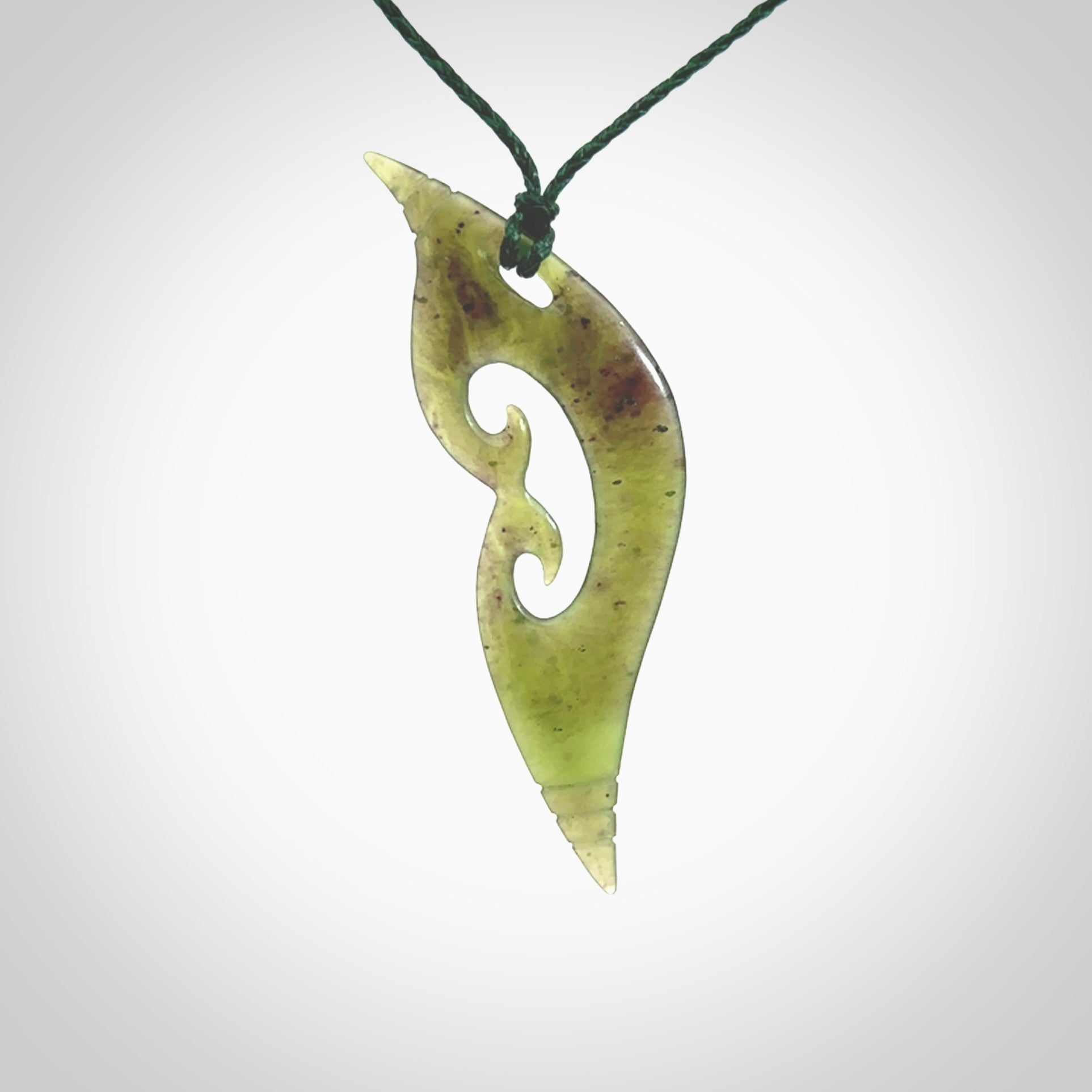 This photo shows a contemporary koru pendant carved from New Zealand Jade. The artist, Shaun Gardiner, has carved this beautifully. We provide this piece with an adjustable green coloured cord. This is a fantastic work of art, we have one only.