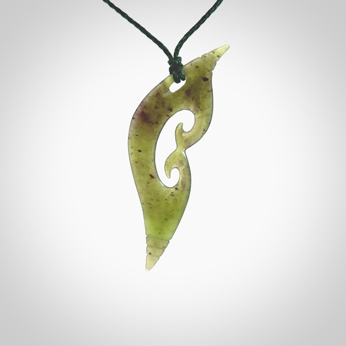 This photo shows a contemporary koru pendant carved from New Zealand Jade. The artist, Shaun Gardiner, has carved this beautifully. We provide this piece with an adjustable green coloured cord. This is a fantastic work of art, we have one only.