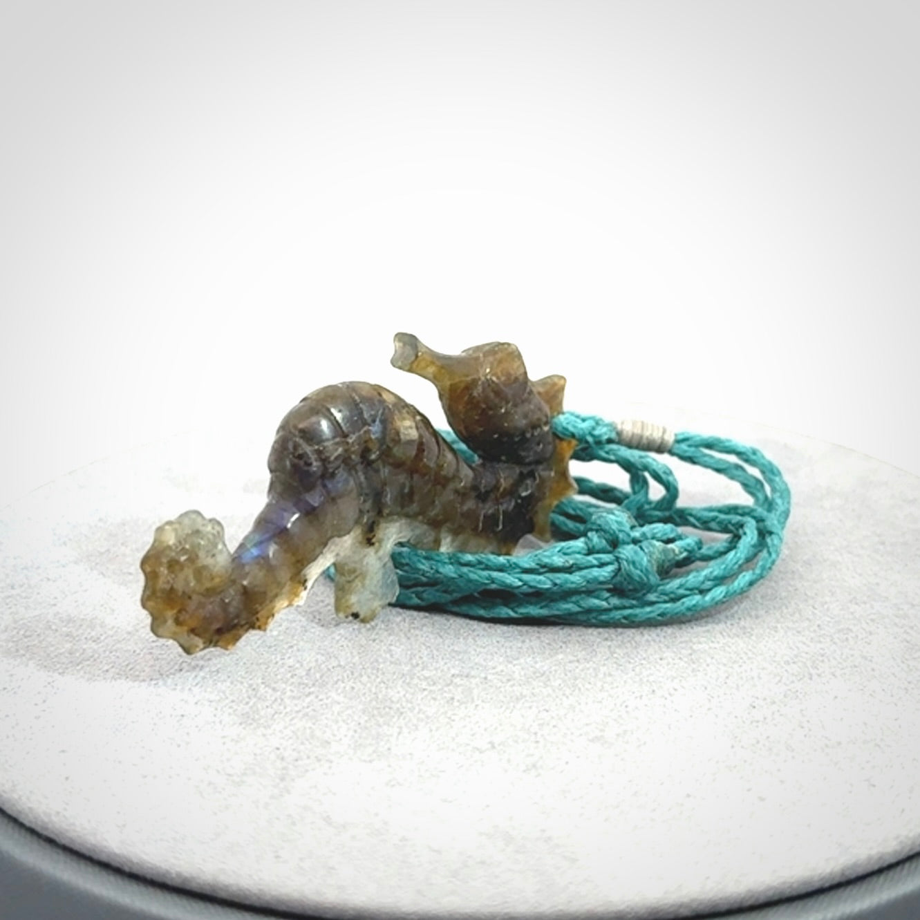 A hand carved labradorite seahorse pendant. We have carved this from beautiful labradorite and we bind them with our hand-plaited cords. The cords are a waxed polyester so they are durable and strong. We ship these worldwide with express courier anywhere in the world.