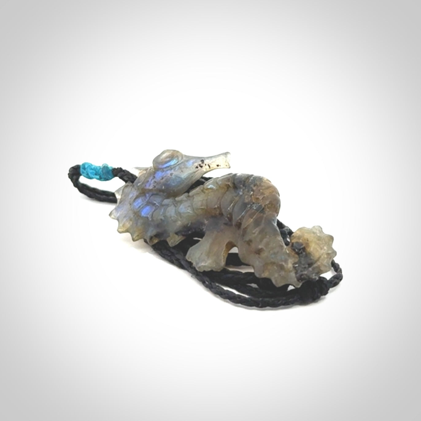 A hand carved labradorite seahorse pendant. We have carved this from beautiful labradorite and we bind them with our hand-plaited cords. The cords are a waxed polyester so they are durable and strong. We ship these worldwide with express courier anywhere in the world.