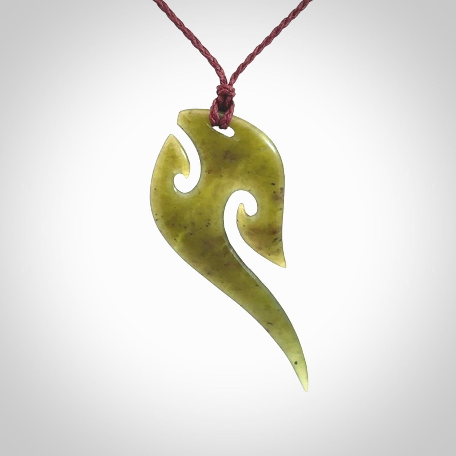 This photo shows a koru pendant carved from New Zealand Jade. We provide this piece with an adjustable plum cord.
