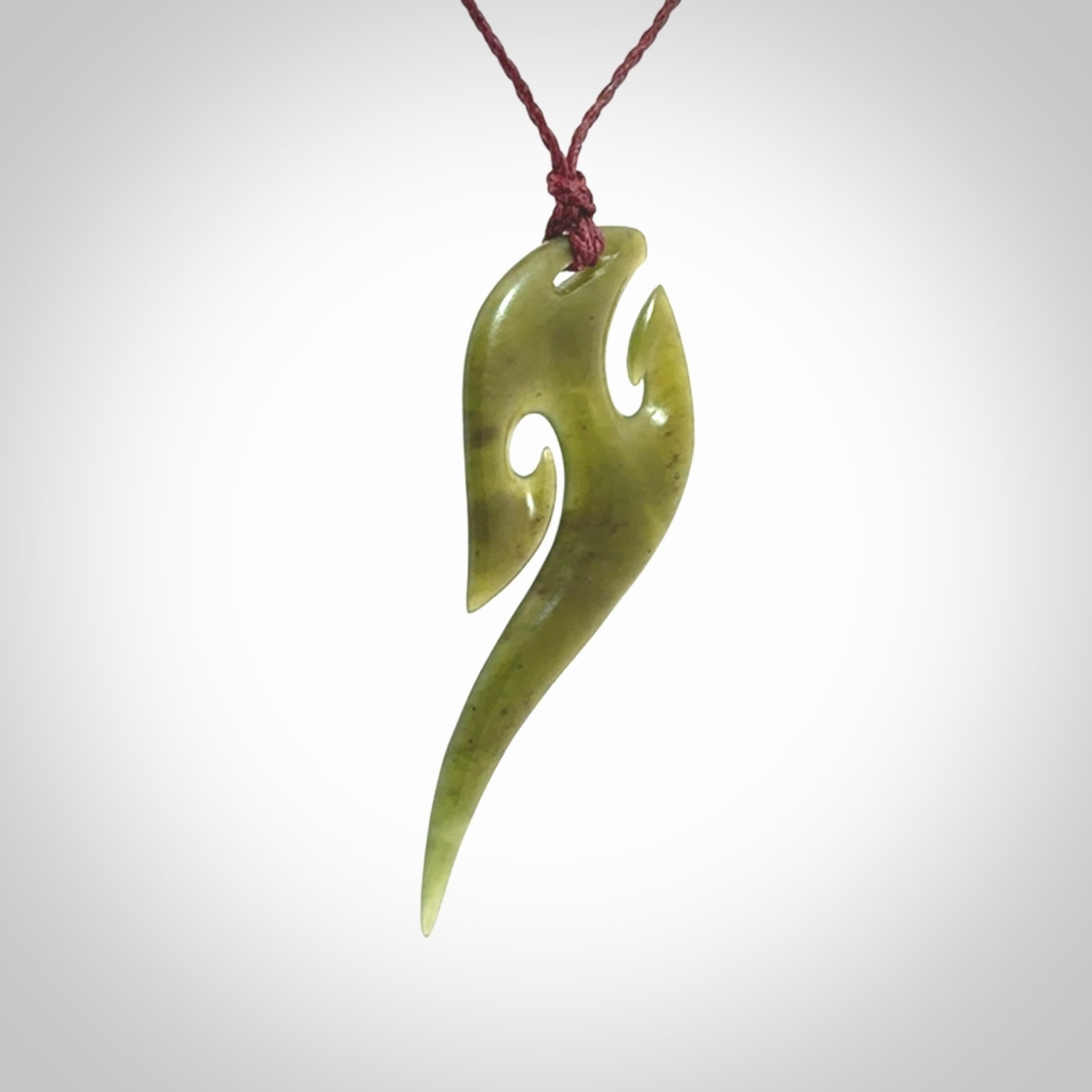 This photo shows a koru pendant carved from New Zealand Jade. We provide this piece with an adjustable plum cord.
