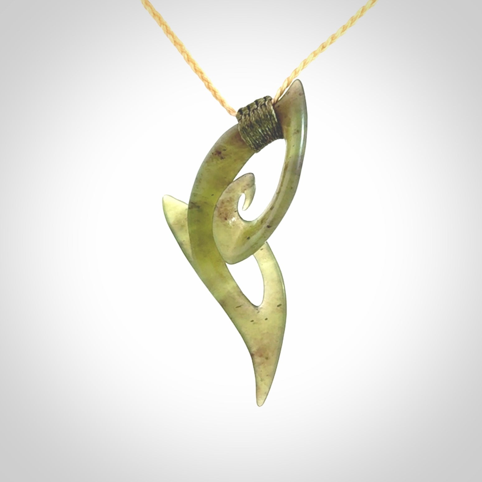 This photo shows a koru pendant carved from New Zealand Jade. We provide this piece with an adjustable oat coloured cord.