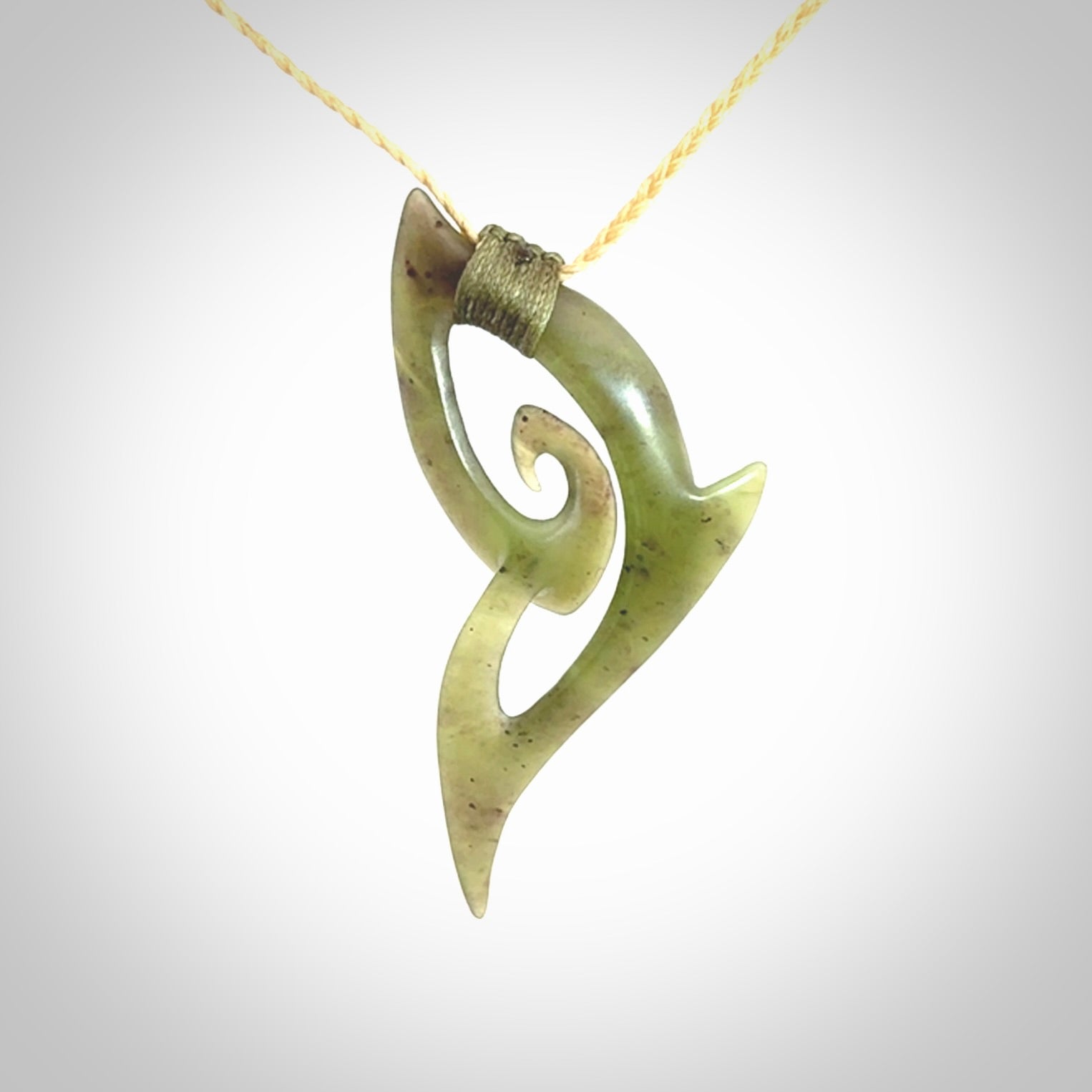 This photo shows a koru pendant carved from New Zealand Jade. We provide this piece with an adjustable oat coloured cord.