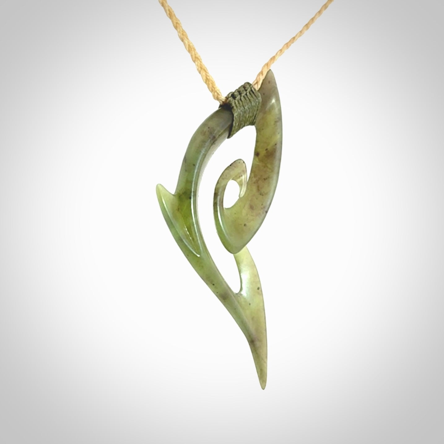 This photo shows a koru pendant carved from New Zealand Jade. We provide this piece with an adjustable oat coloured cord.