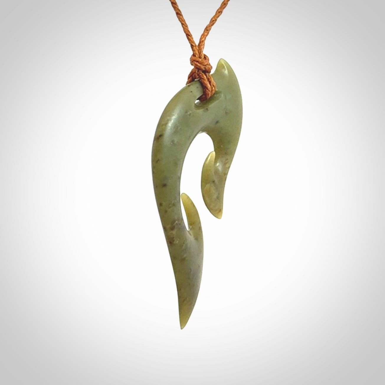 This photo shows a koru pendant carved from New Zealand Jade. We provide this piece with an adjustable gingernut brown coloured cord.