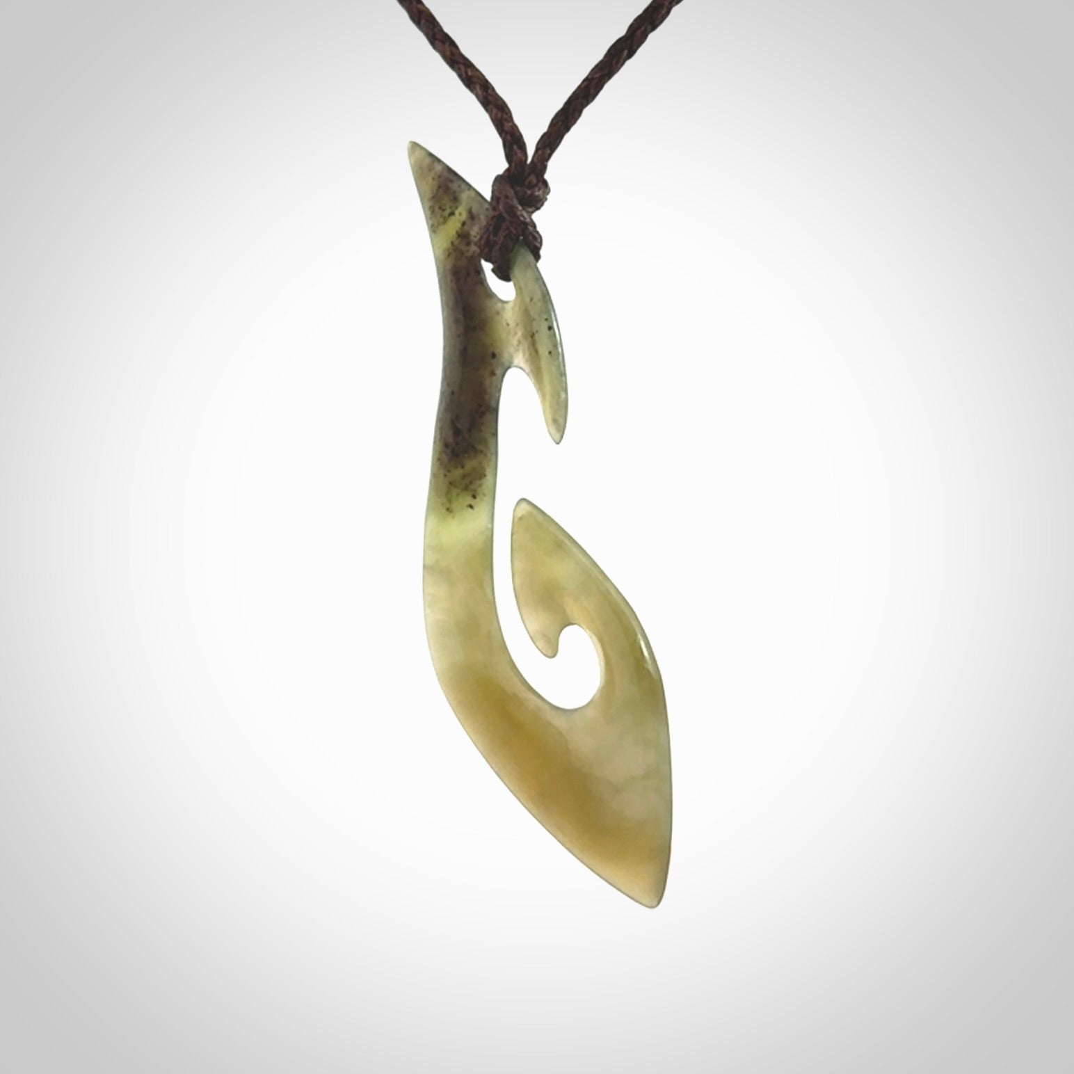 This photo shows a large contemporary matau pendant carved from New Zealand Jade. The artist, Shaun Gardiner, has carved this beautifully. We provide this piece with an adjustable dark brown coloured cord. This is a fantastic work of art, we have one only.