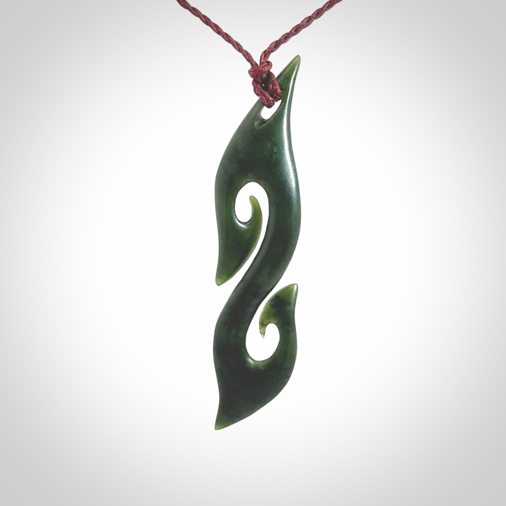 This photo shows a contemporary S shaped pendant carved from New Zealand Jade. The artist, Shaun Gardiner, has carved this beautifully. We provide this piece with an adjustable plum cord. This is a fantastic work of art, we have one only.