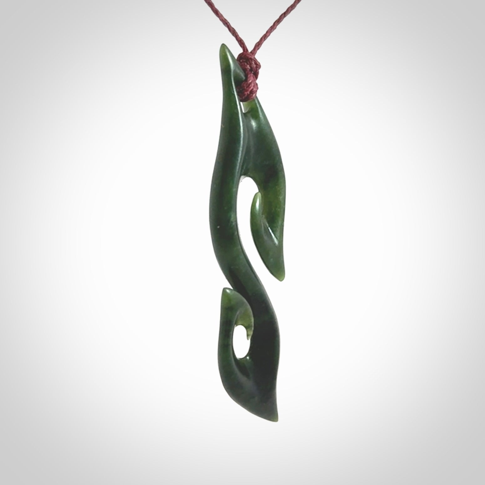 This photo shows a contemporary S shaped pendant carved from New Zealand Jade. The artist, Shaun Gardiner, has carved this beautifully. We provide this piece with an adjustable plum cord. This is a fantastic work of art, we have one only.
