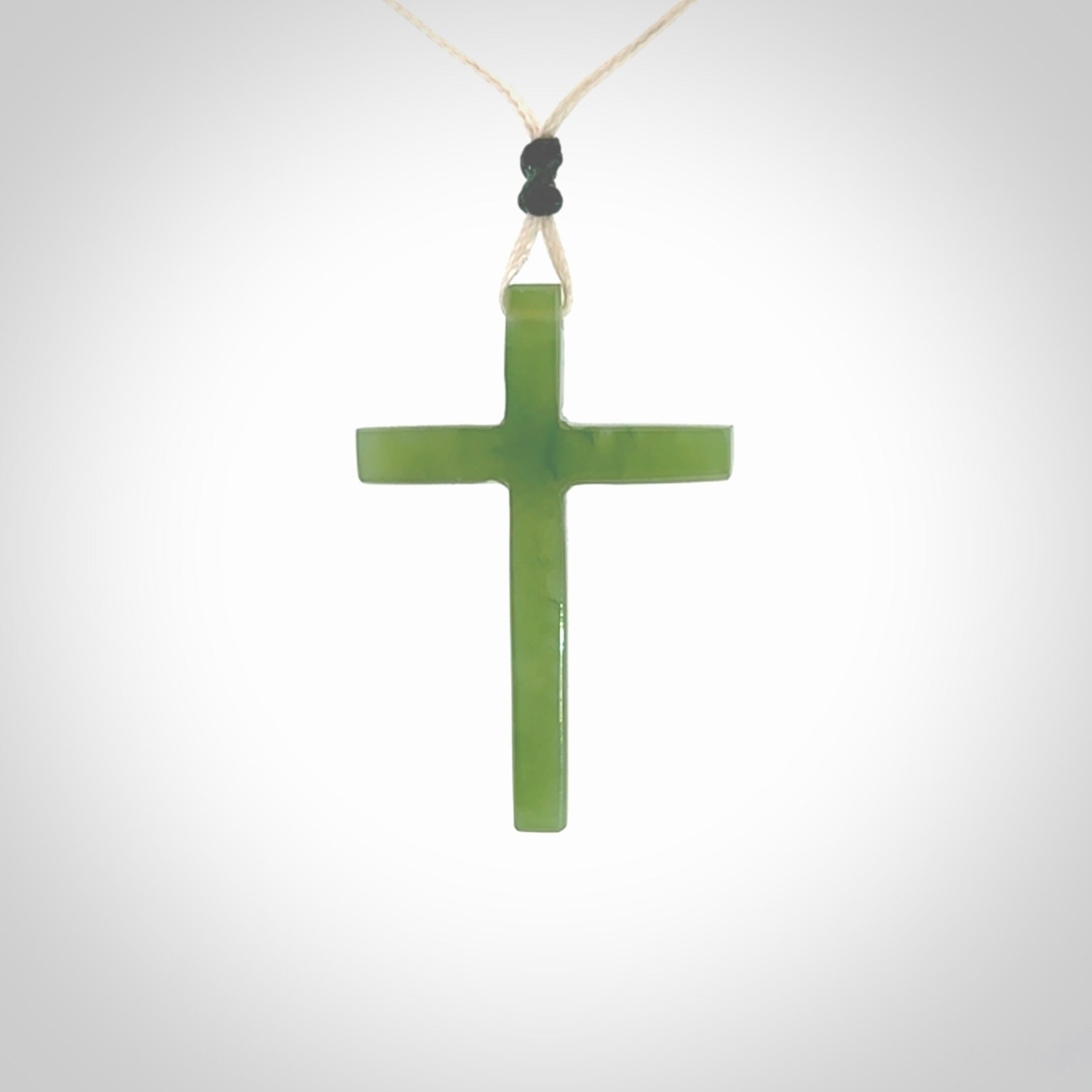 Hand carved jade cross. Made from New Zealand jade. Christian cross for sale online.This picture shows a green jade cross suspended on a fine, plaited cord. The cross is hand carved jade cross. Made from New Zealand jade. Christian cross for sale online.