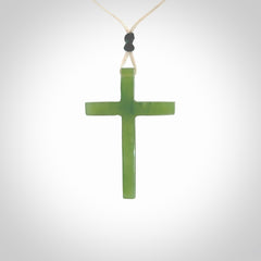 Hand carved jade cross. Made from New Zealand jade. Christian cross for sale online.This picture shows a green jade cross suspended on a fine, plaited cord. The cross is hand carved jade cross. Made from New Zealand jade. Christian cross for sale online.