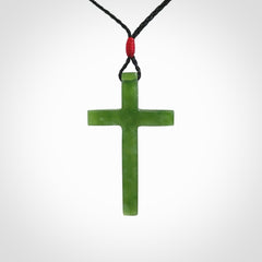 Hand carved jade cross. Made from New Zealand jade. Christian cross for sale online.This picture shows a green jade cross suspended on a fine, plaited cord. The cross is hand carved jade cross. Made from New Zealand jade. Christian cross for sale online.