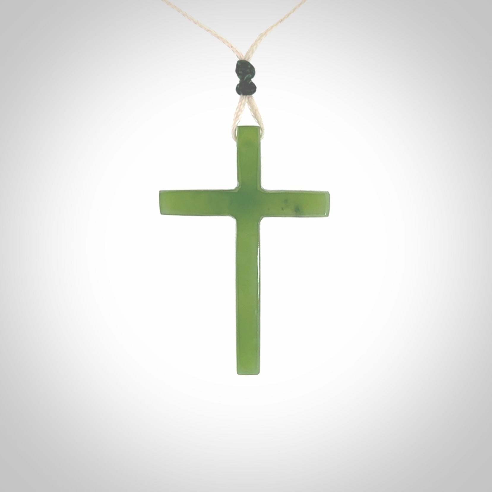 Hand carved jade cross. Made from New Zealand jade. Christian cross for sale online.This picture shows a green jade cross suspended on a fine, plaited cord. The cross is hand carved jade cross. Made from New Zealand jade. Christian cross for sale online.