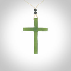 Hand carved jade cross. Made from New Zealand jade. Christian cross for sale online.This picture shows a green jade cross suspended on a fine, plaited cord. The cross is hand carved jade cross. Made from New Zealand jade. Christian cross for sale online.
