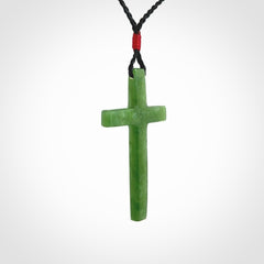 Hand carved jade cross. Made from New Zealand jade. Christian cross for sale online.This picture shows a green jade cross suspended on a fine, plaited cord. The cross is hand carved jade cross. Made from New Zealand jade. Christian cross for sale online.
